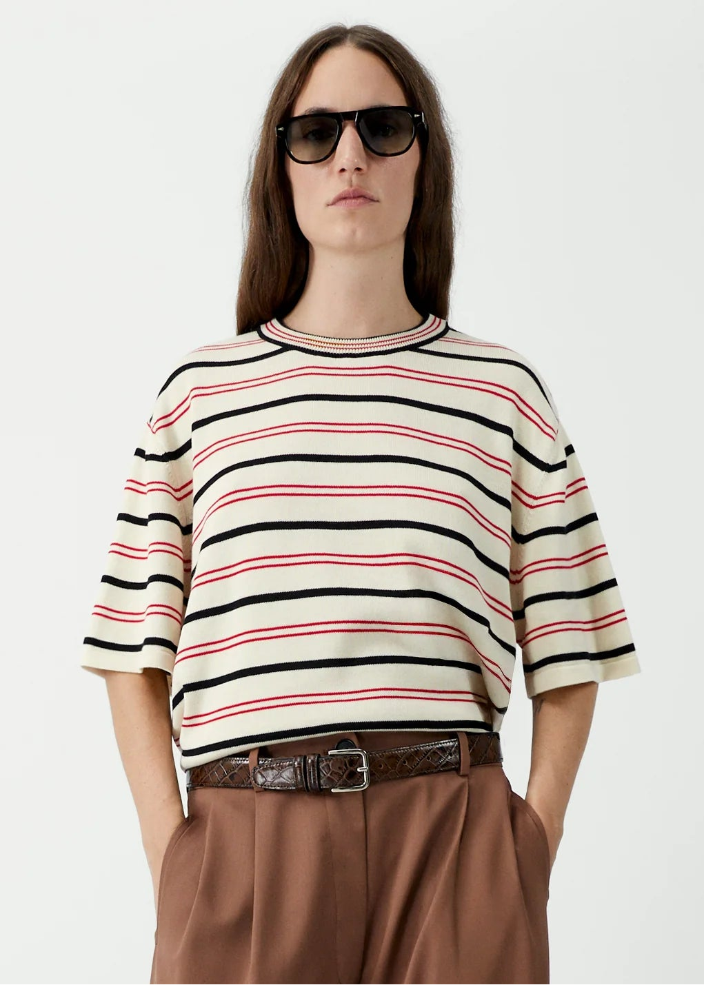 Person wearing a striped sweater and brown pants on a white background