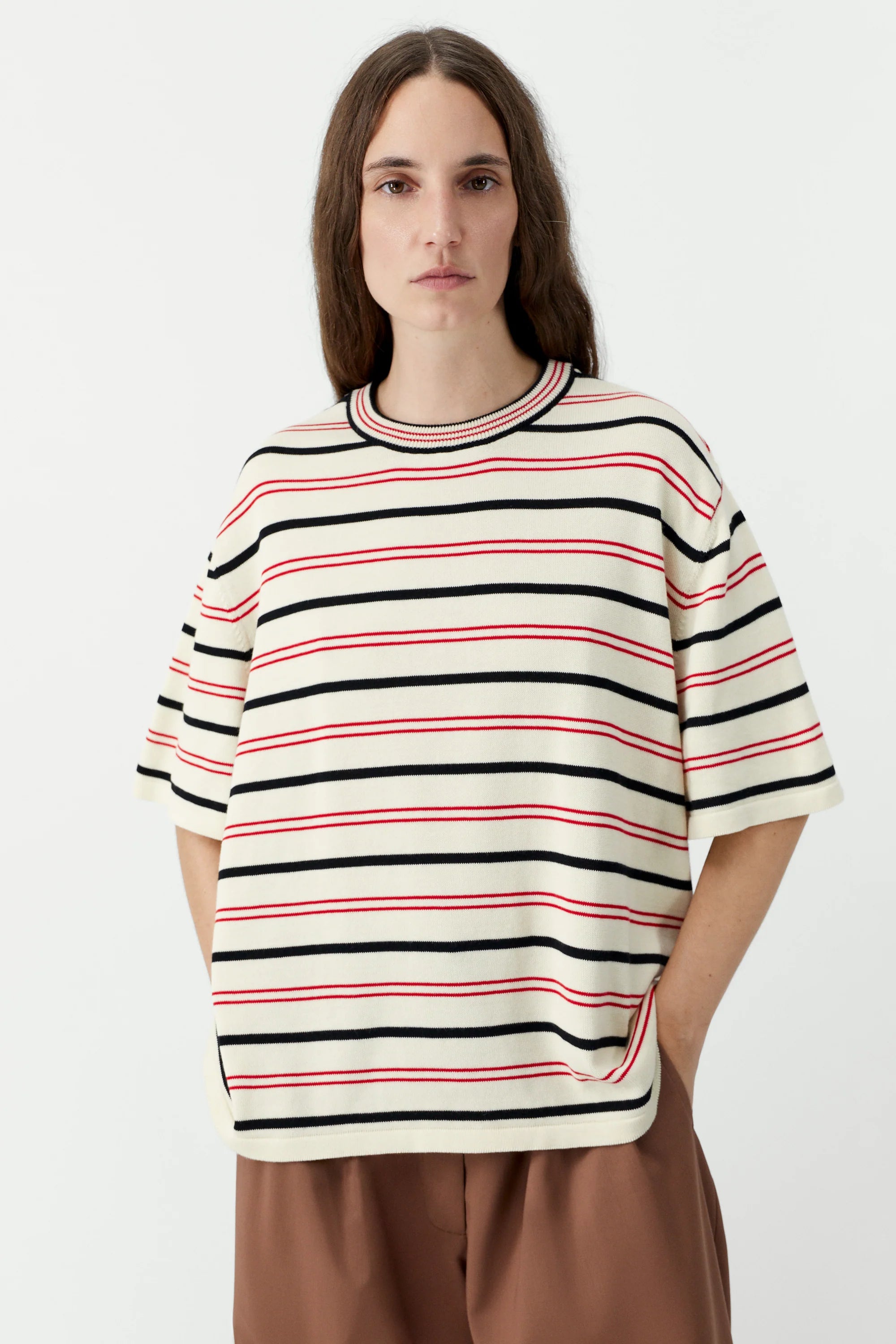 Person wearing a striped shirt with red, black, and white horizontal lines on a plain background
