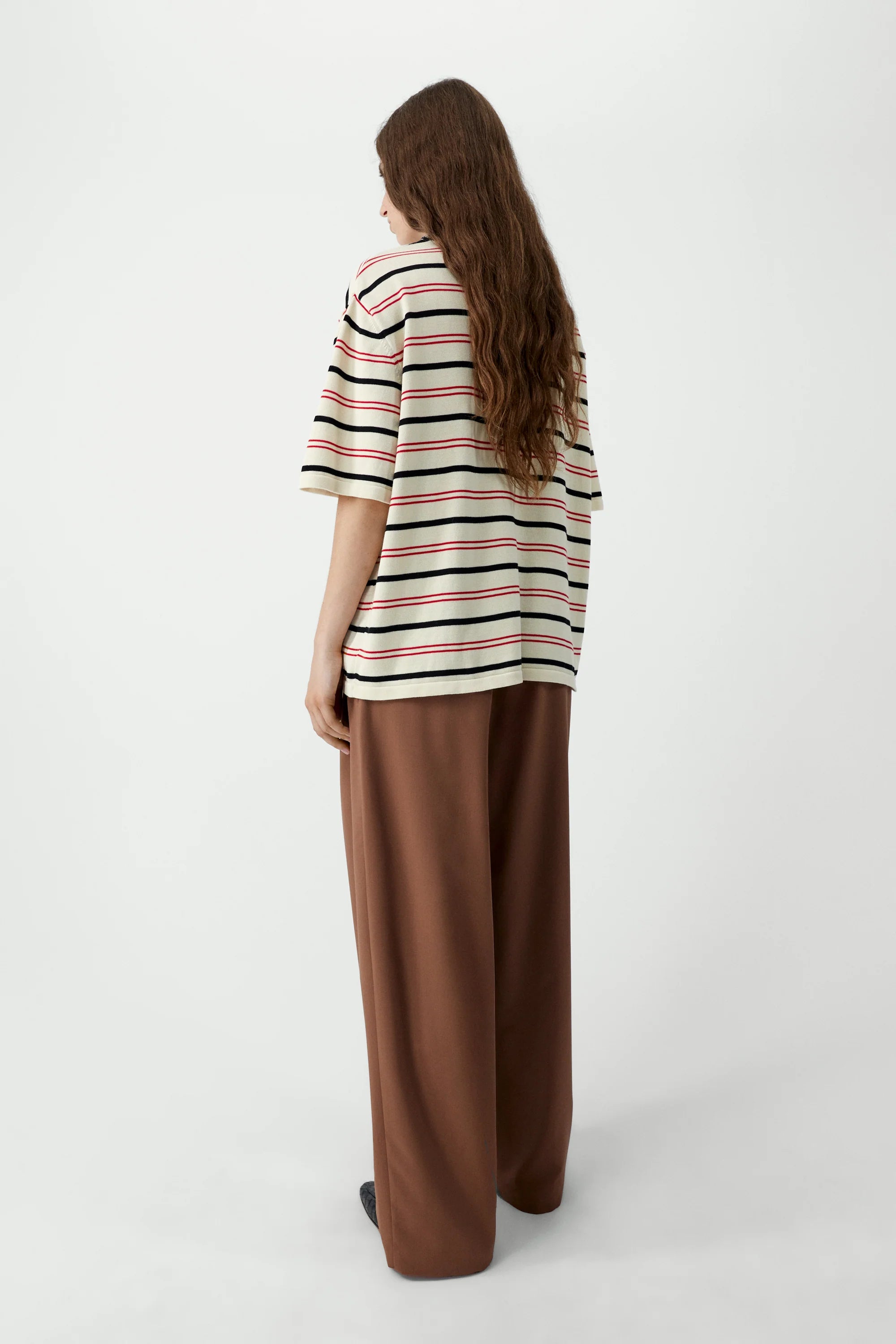 Person wearing a striped shirt and brown pants on a white background