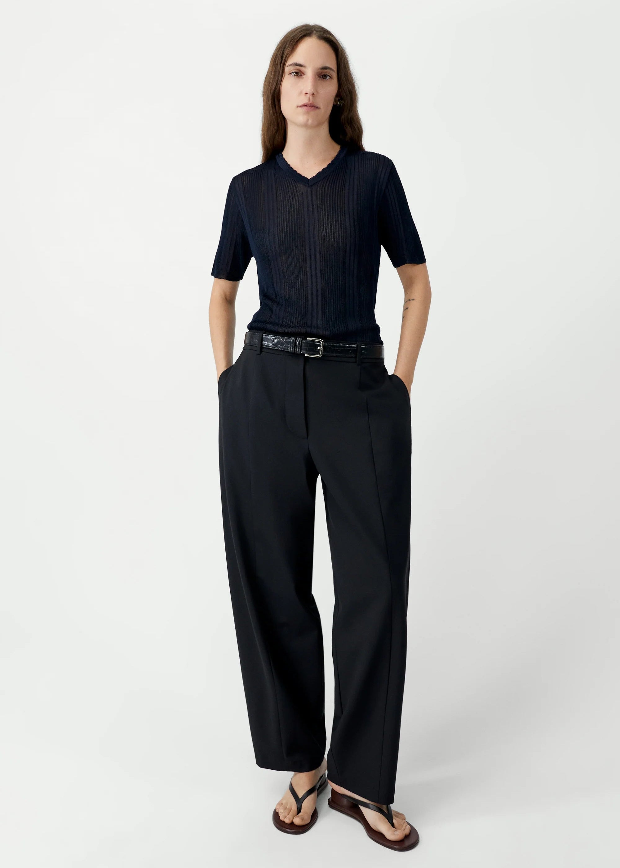 Person wearing a black outfit with a belt on a white background