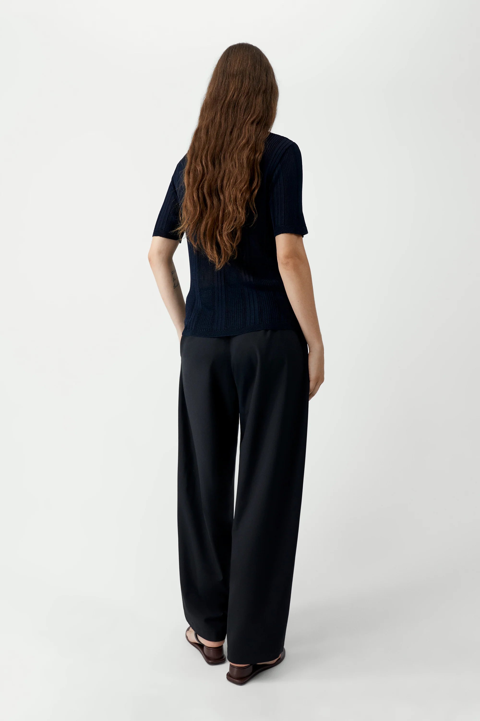 Person wearing a black outfit with wide-leg pants on a white background