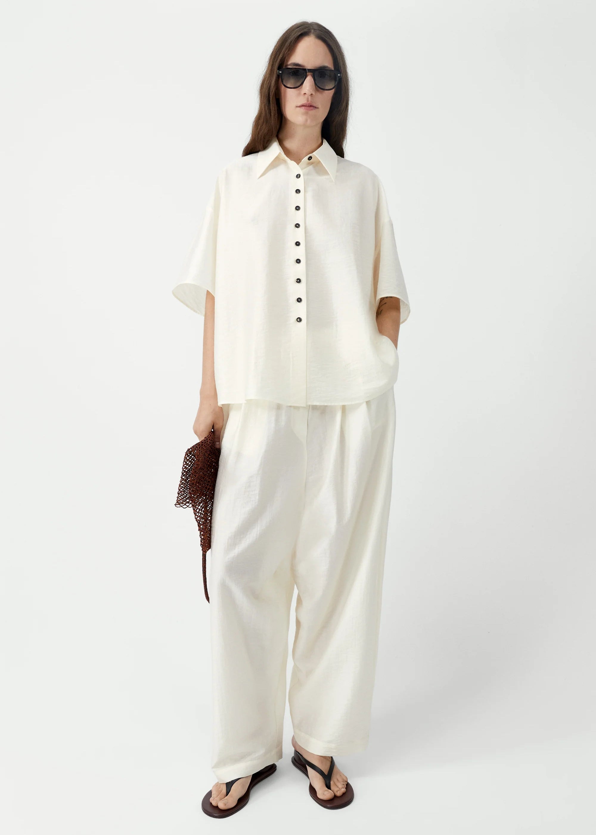 Woman wearing a white outfit with sunglasses on a white background