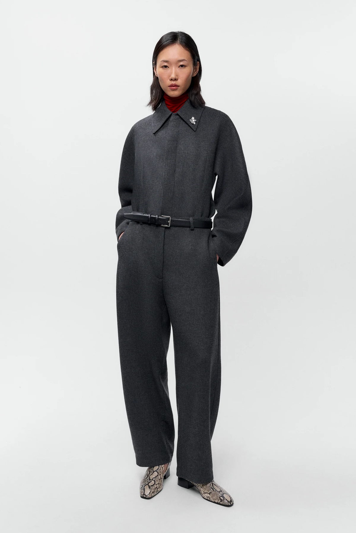 Person wearing a dark gray outfit on a white background