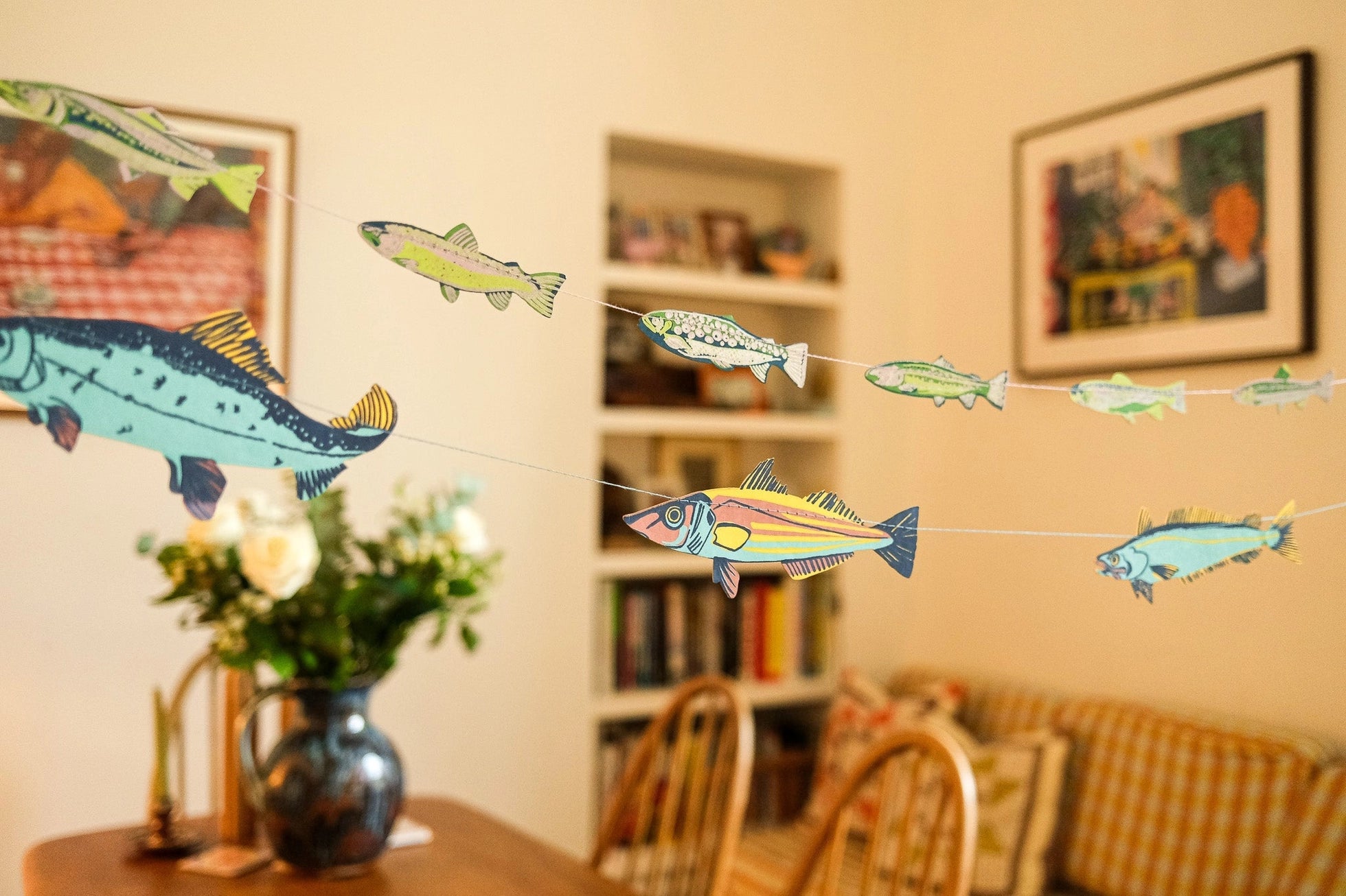 Decorative string with colorful fish shapes hanging in a room with furniture and decor.