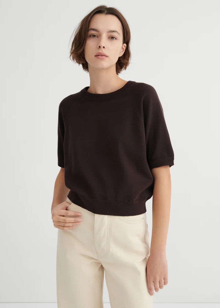 model with brown short sleeve top and white jeans