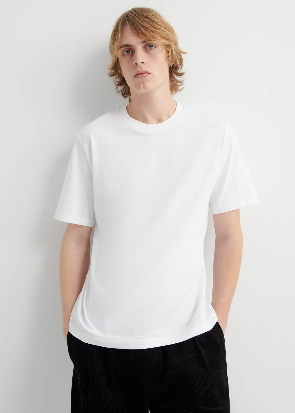 Person wearing a plain white t-shirt against a light gray background